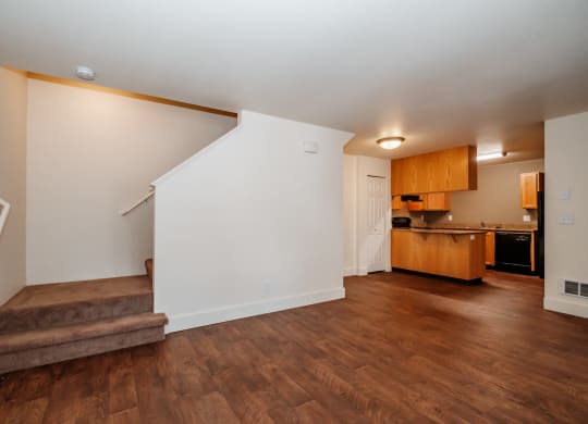 a living room with a staircase and a kitchen in the background