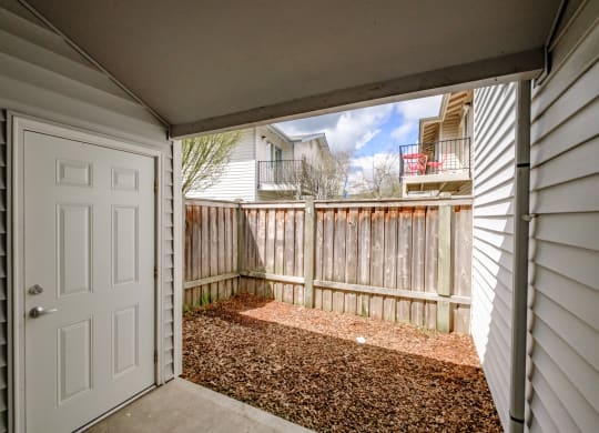 a white door opens to a small patio with a wooden fence
