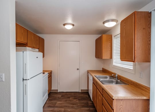 a kitchen with a white refrigerator freezer next to a sink and a window