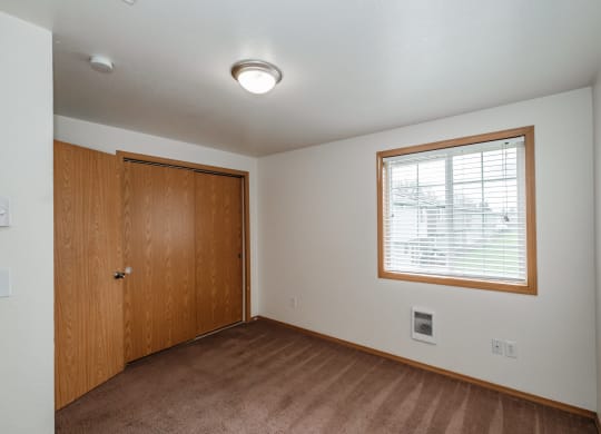 an empty bedroom with a large window and a wooden door
