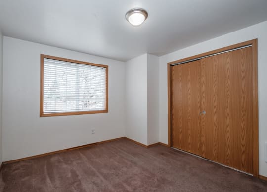 an empty bedroom with a large window and a wooden door