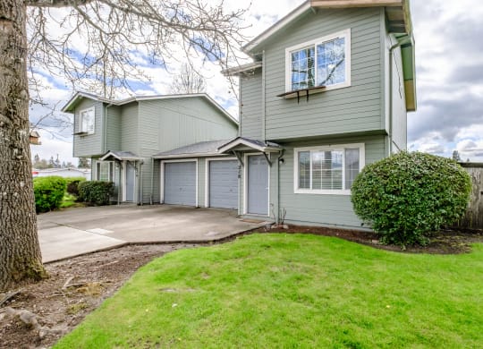 a gray house with a gray garage and a green lawn
