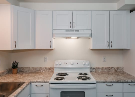 a kitchen with white cabinets and a white stove top oven