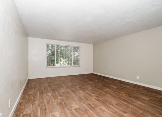 a bedroom with hardwood floors and a large window