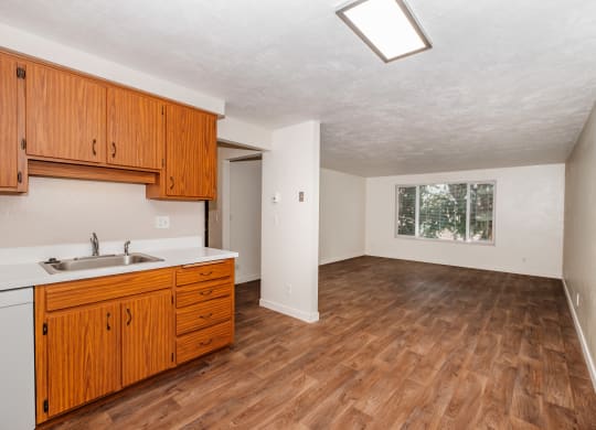 a kitchen and living room with hardwood floors and white walls