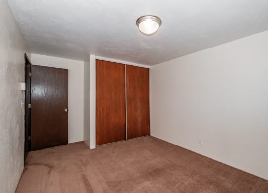 a bedroom with a carpeted floor and a door to a closet