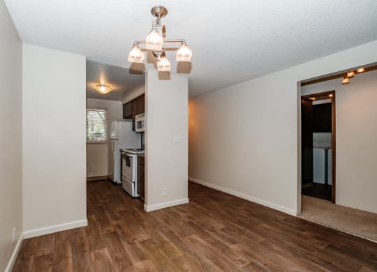 a living room with hardwood floors and a kitchen in the background