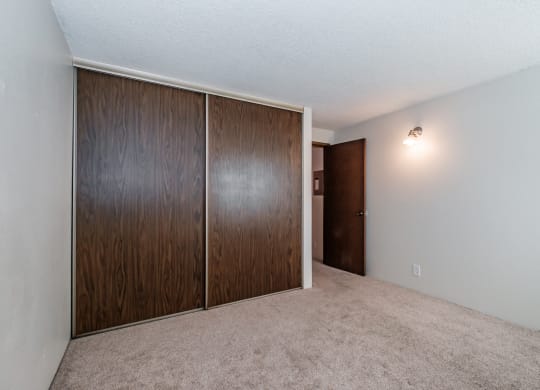an empty bedroom with a wardrobe and an open door
