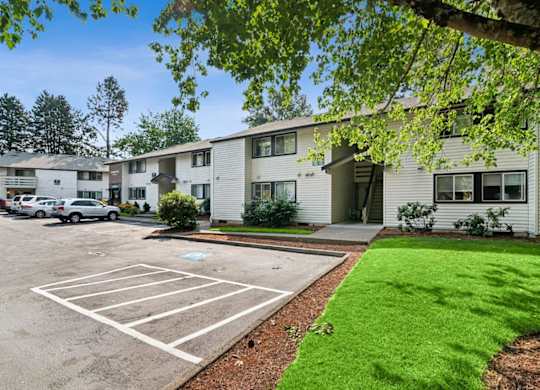 A parking lot in front of a building with a green lawn.