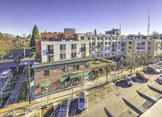 A parking lot with cars and a building with a green awning in the background.