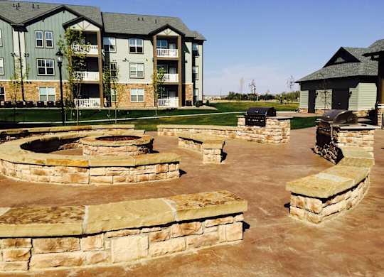 A large stone patio with a fire pit in the middle.