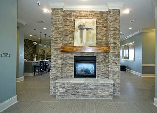 A stone fireplace with a painting above it in a room.
