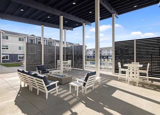 A patio with white furniture and a black awning.
