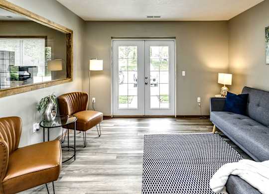 A living room with a grey couch, two chairs, and a rug.