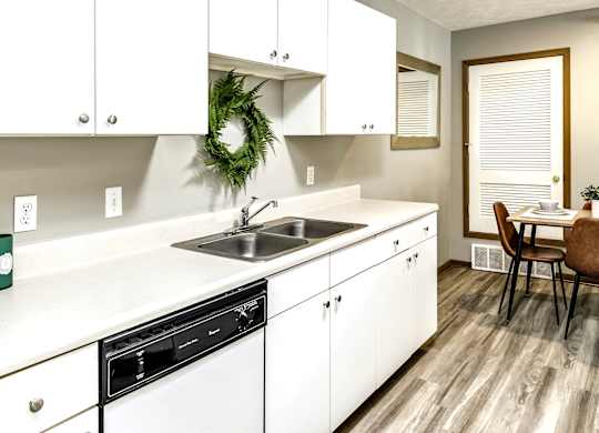 A kitchen with white cabinets and a wreath on the wall.