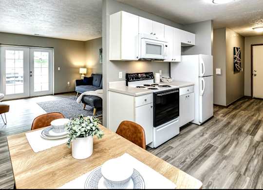 A modern kitchen with white appliances and a dining table set for two.