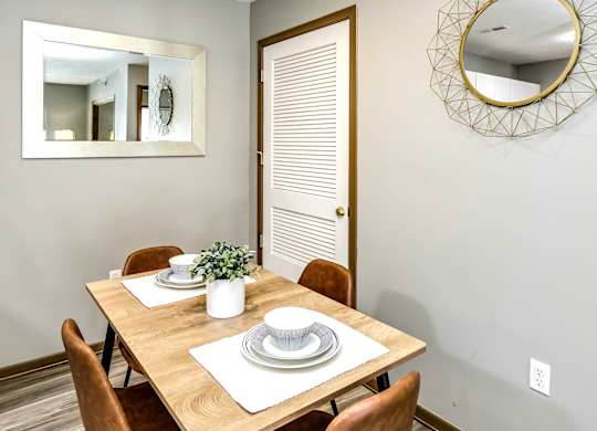 A dining room with a wooden table set for two.