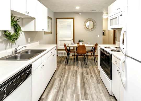 A modern kitchen with white appliances and wooden flooring.