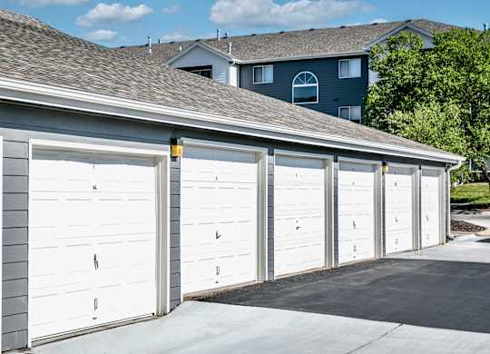 A row of white garage doors in front of a house.