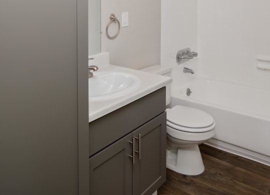 a bathroom with gray cabinets and a white bathtub