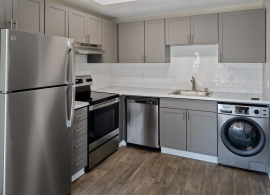 a kitchen with gray cabinets and stainless steel appliances