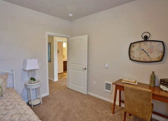 a bedroom with a bed and a desk with a clock