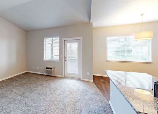 an empty living room with a kitchen and a door