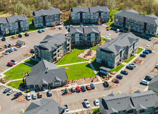 A bird's eye view of a parking lot with cars and apartment buildings.