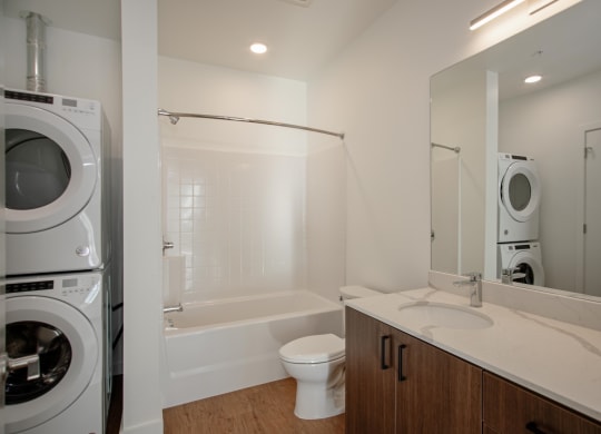 a bathroom with a washer and dryer in it and a toilet and sink