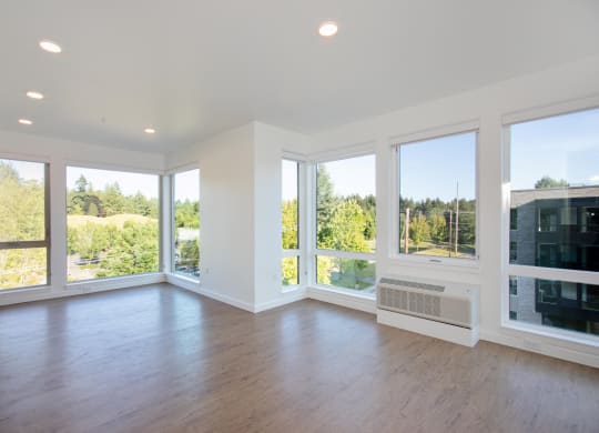 an empty living room with large windows and a wood floor