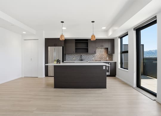 A modern kitchen with a large island and pendant lights.