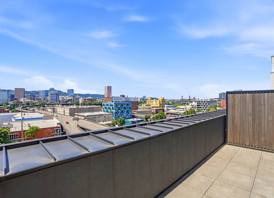 A rooftop with a metal railing and a view of a city skyline.