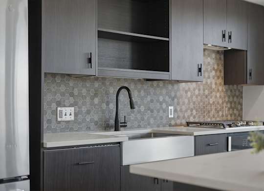 A modern kitchen with a white countertop and dark grey cabinets.