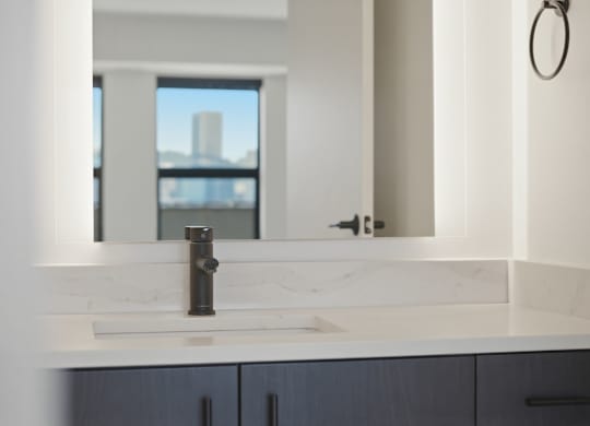 A bathroom sink with a marble counter top and a large mirror.