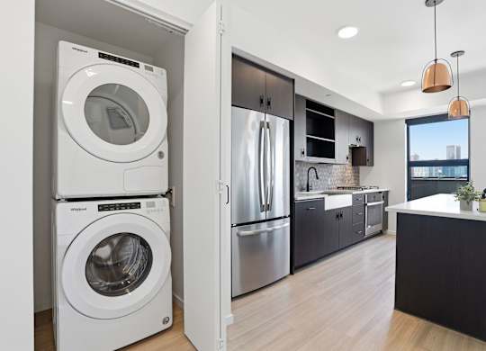 A modern kitchen with a washer and dryer built into the cabinetry.