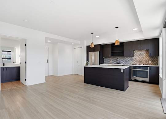 A modern kitchen with a black countertop and wooden flooring.