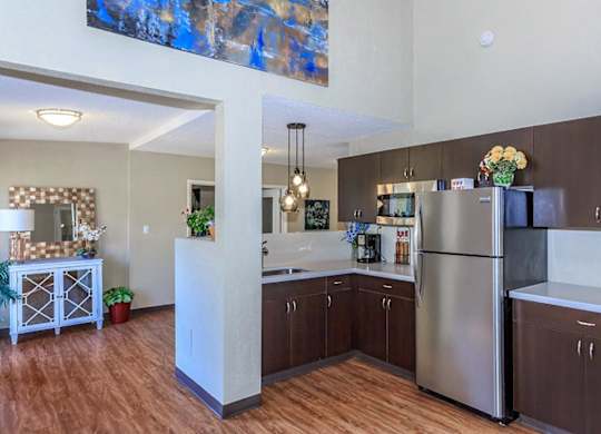 A kitchen with a refrigerator, sink, and wooden floors.