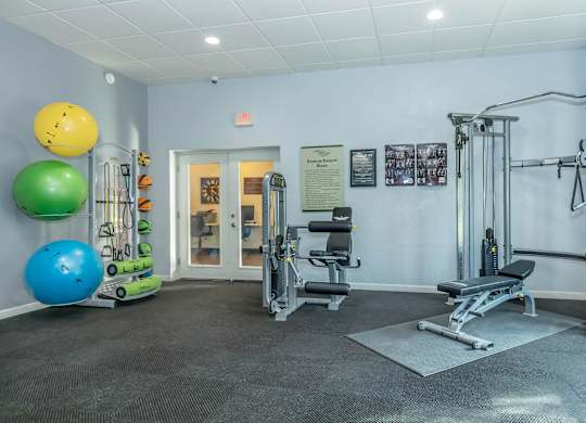 A gym with a variety of equipment including a leg press machine, a bench press, and a squat rack.