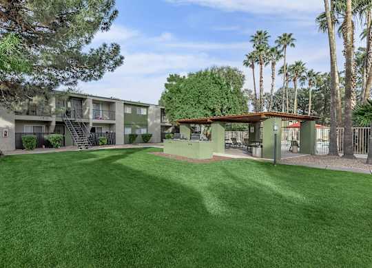 A grassy area in front of a building with palm trees in the background.