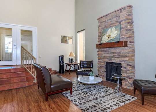 A living room with a stone fireplace and a painting of a white flower above it.