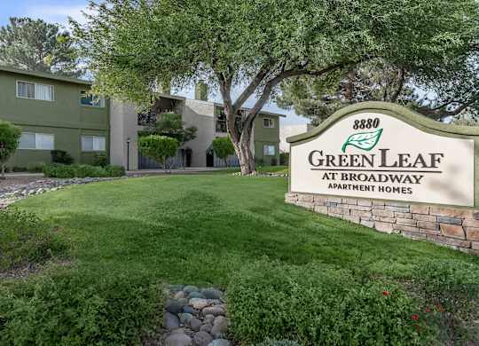 A sign for Green Leaf Apartments is in front of a building.