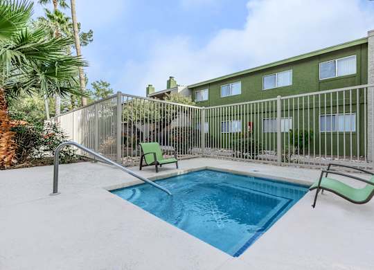 A pool surrounded by a fence and chairs.