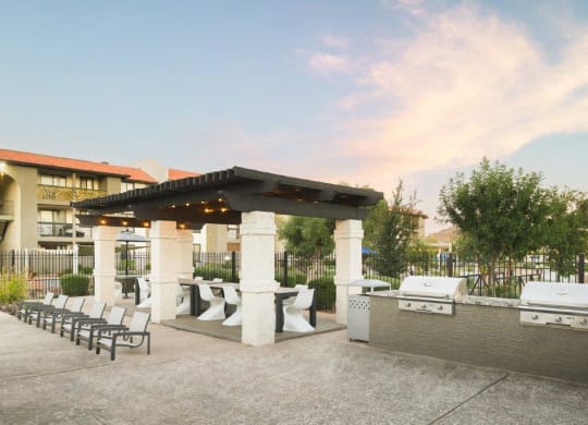 a patio with a grill and tables and chairs