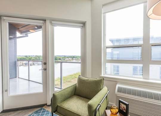 A green chair sits in a room with a view of the outside.