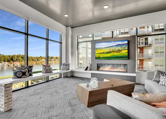 A modern living room with a fireplace and a large window overlooking a lake.