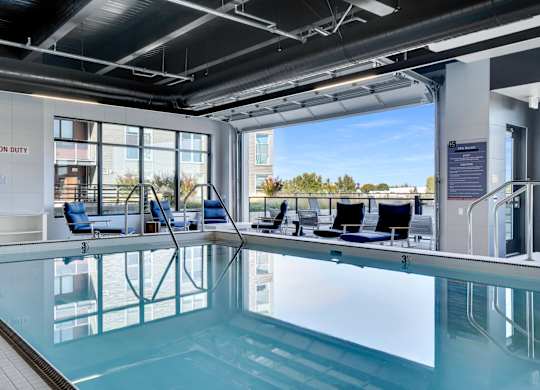 A swimming pool inside a building with a view of the outdoors.