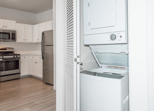 a kitchen with white cabinets and a white washer and dryer