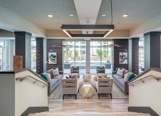 a lobby with couches and chairs and a pool in the background