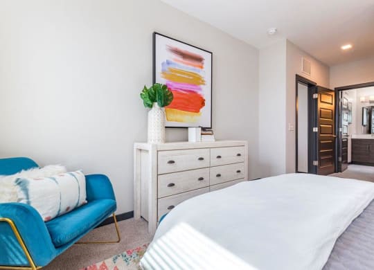 a bedroom with a white bed and a blue chair