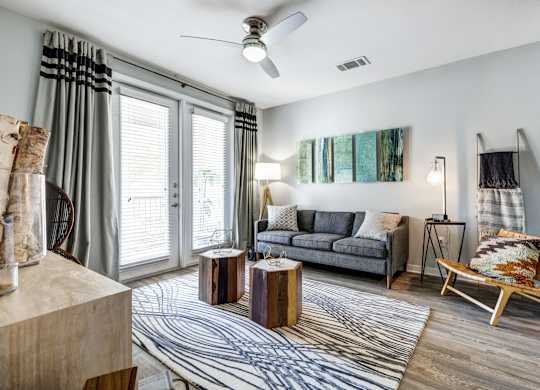 A living room with a grey couch, a wooden coffee table, and a striped rug.